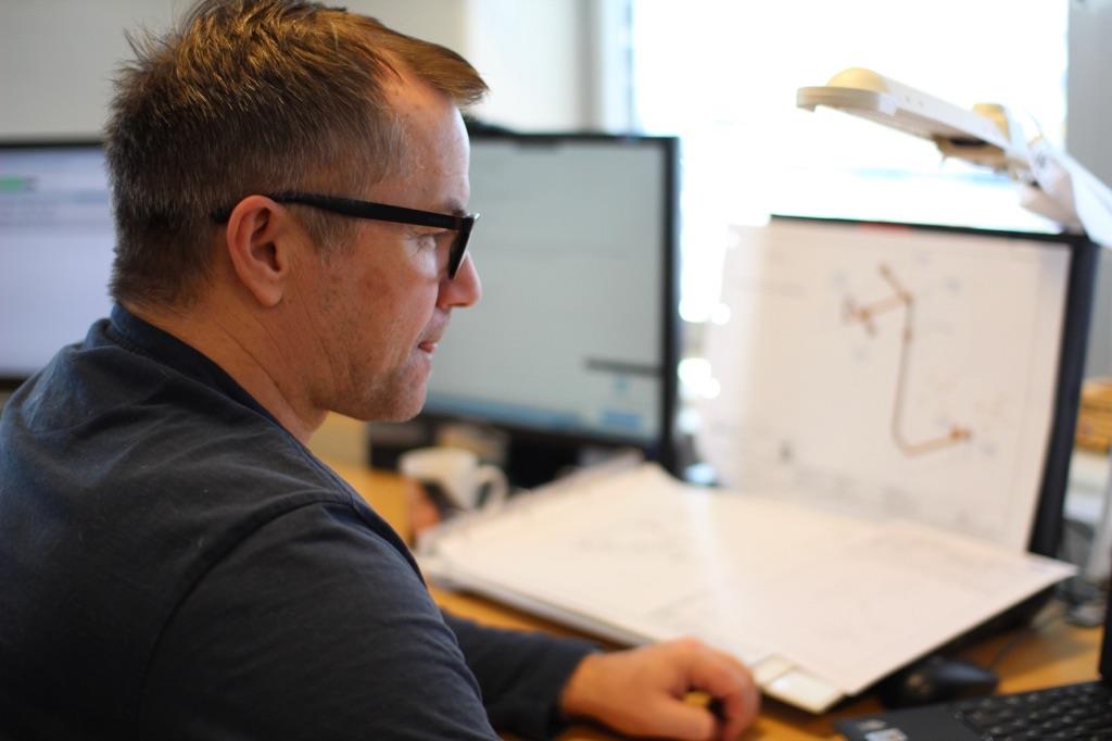 IRV-ansatt sitter med tegninger på kontoret